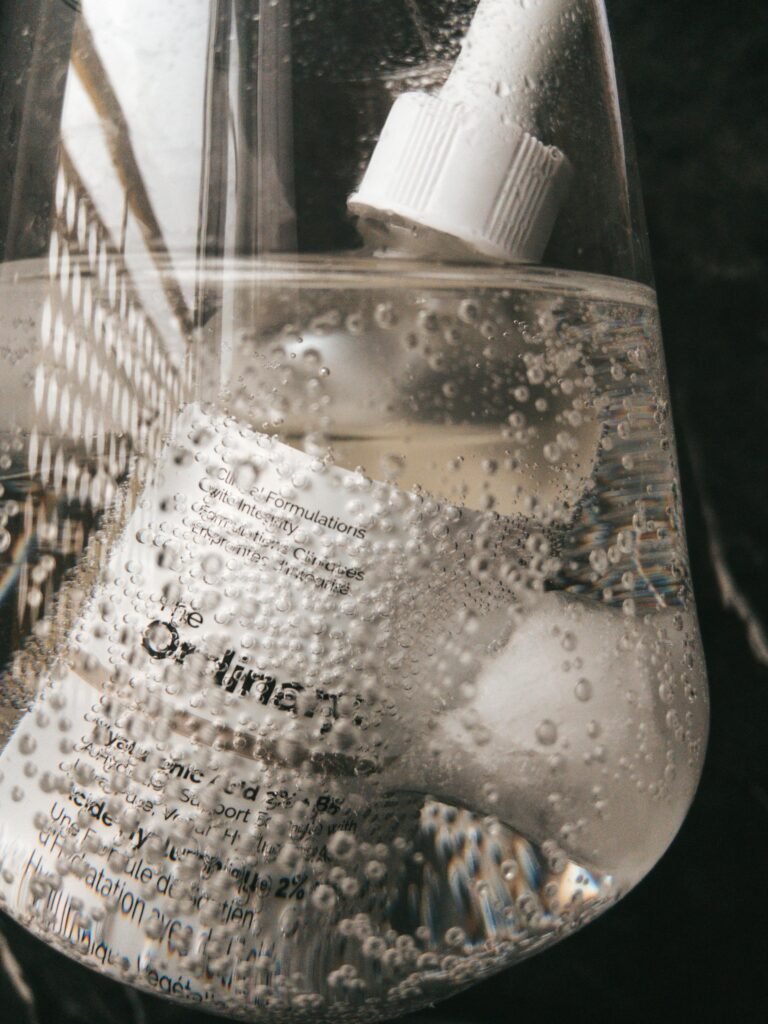 Artistic capture of a skincare dropper bottle submerged in sparkling water bubbles.